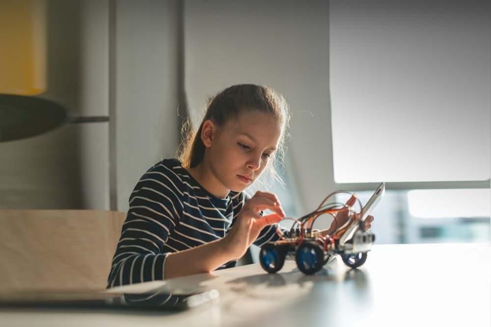 Young female student building a robotic car during an online technology class at Great Lakes Learning Academy